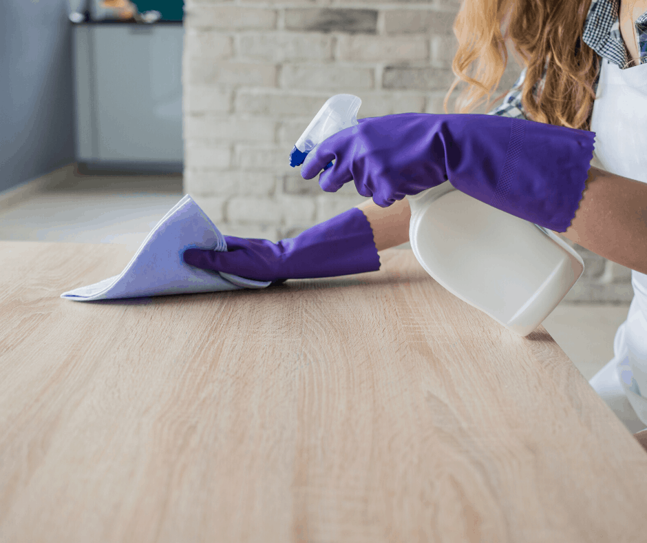 woman cleaning counter with spray bottle and microfiber towel
